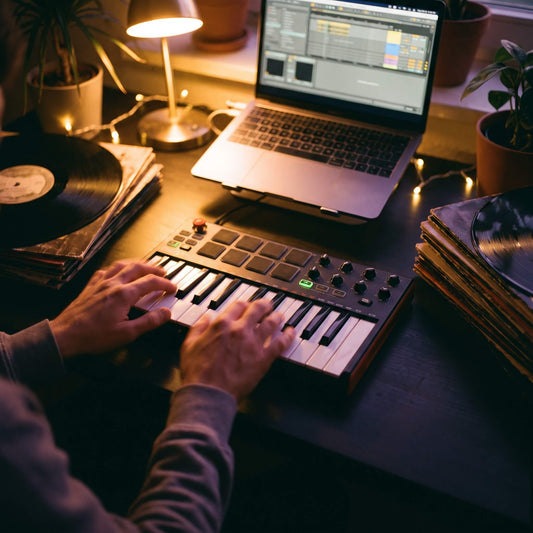 Producer using a MIDI controller and laptop to work with Ripchord presets in a warm home studio setup