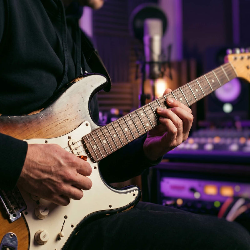 Producer recording live R&B guitar loops in a home studio